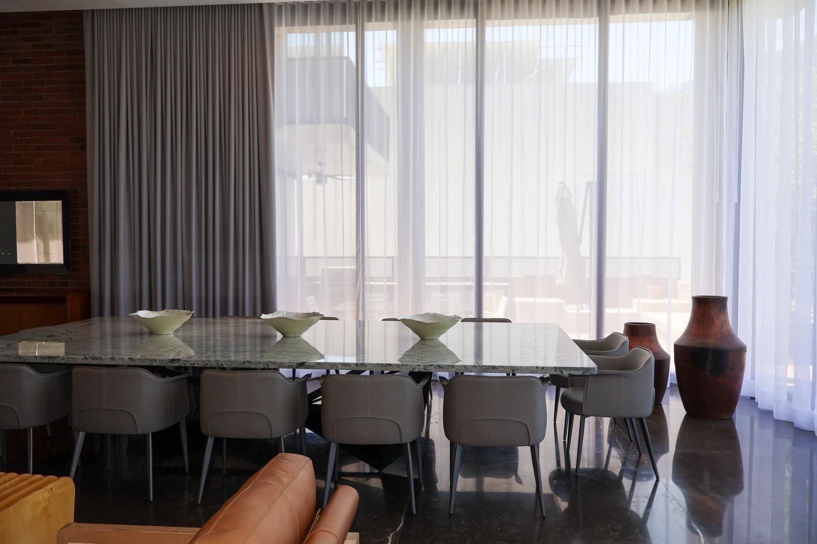 The Gardenia dining room — a green marble table against sheer linen and exposed brick